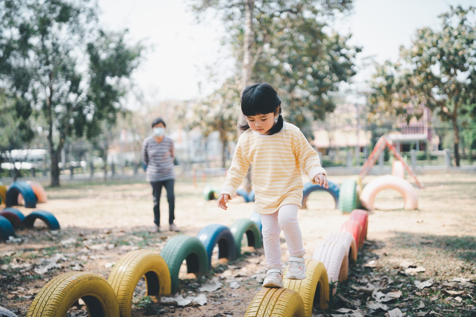 young asian mother wearing surgical mask playing with her baby o