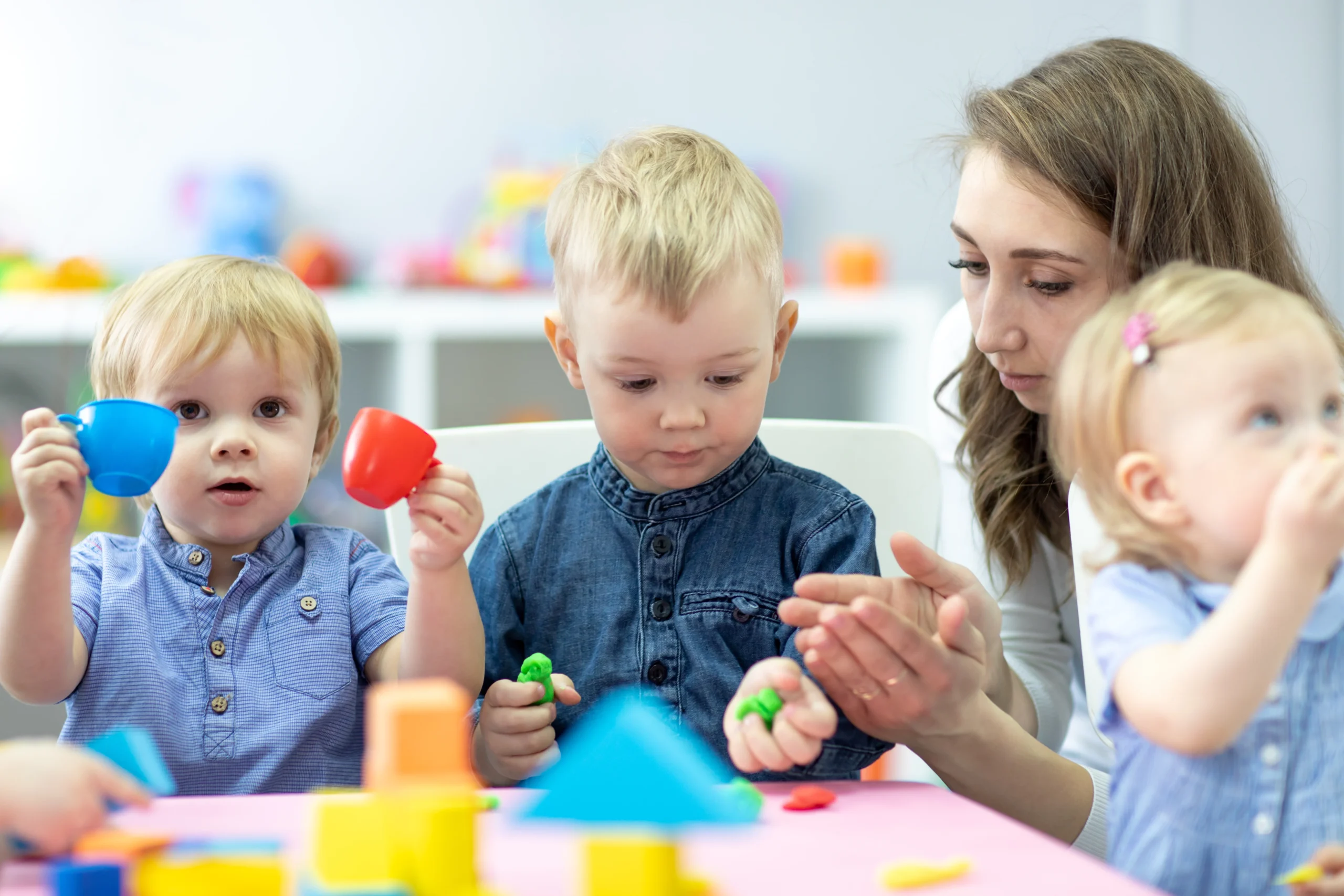 Little kids molded from clay toys. Teacher play with children.