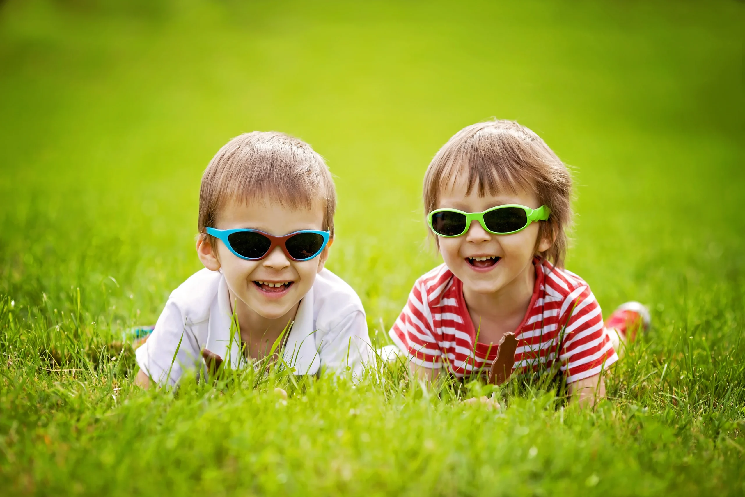 Cute kids with sunglasses, eating chocolate lollipops at the park
